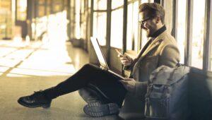 man texting while using laptop